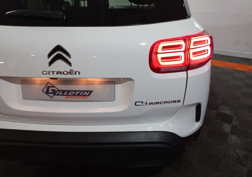 Vue arrière droite d'un Citroën C5 Aircross blanc avec feux arrière LED allumés et logo visible.