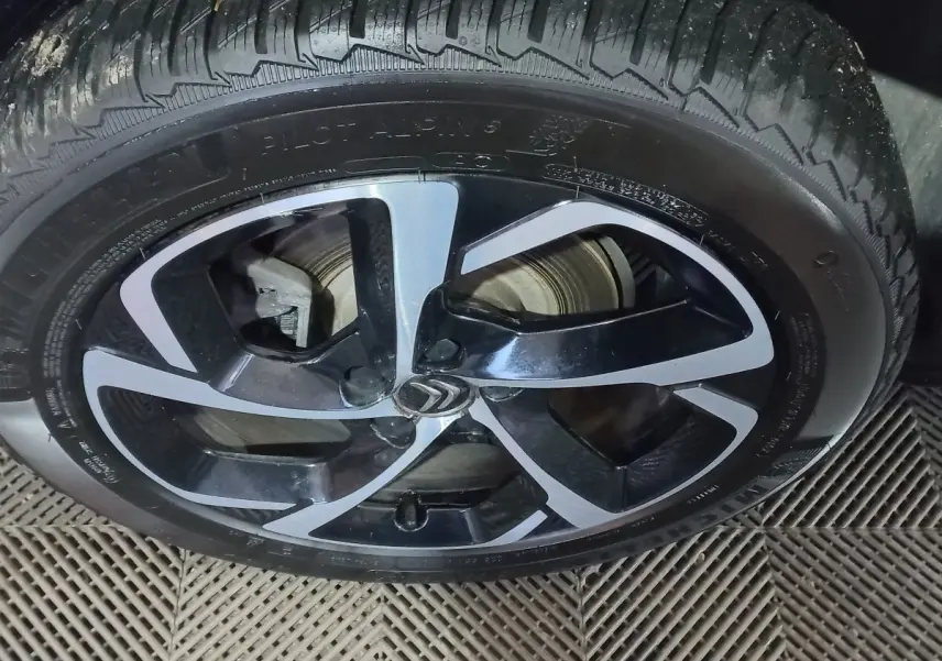 Gros plan sur la jante alliage noire et argentée avec logo Citroën d’un Citroën C5 Aircross blanc.