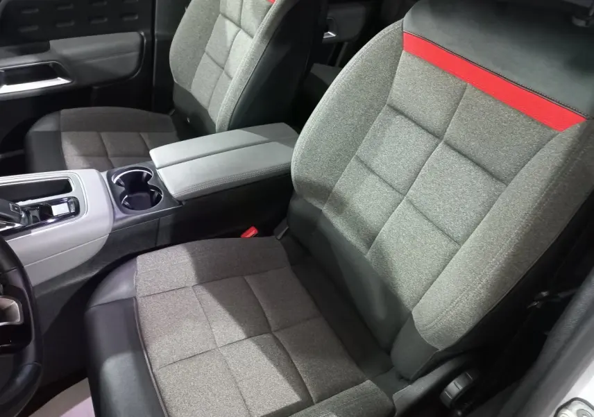 Vue rapprochée des sièges avant gris avec surpiqûres rouges et console centrale du Citroën C5 Aircross blanc.