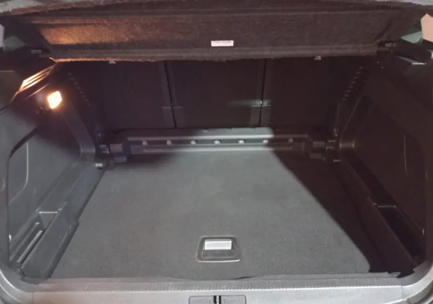 Coffre ouvert du Citroën C5 Aircross blanc 2020, vue intérieure montrant un espace de rangement noir et éclairé à gauche.