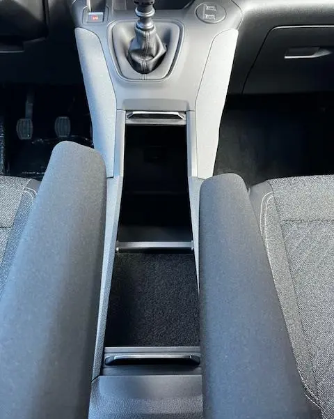 Vue plongeante sur la console centrale grise et les accoudoirs noirs du Peugeot Rifter 2024, boîte manuelle.