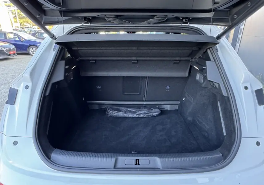 Coffre ouvert d’un DS7 Crossback blanc, vue arrière montrant l’espace de chargement et la tablette cache-bagages.
