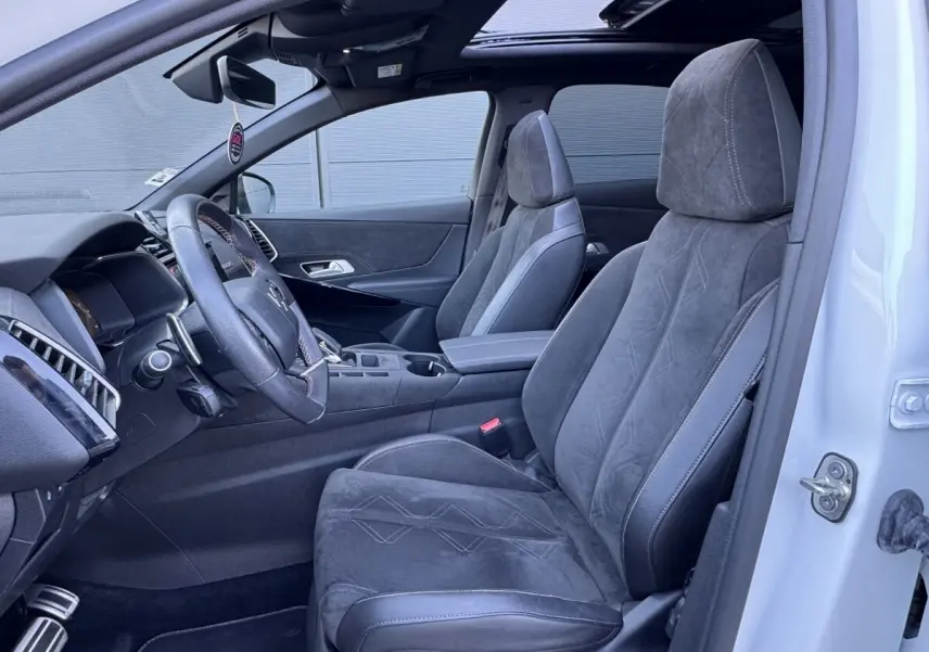 Intérieur côté conducteur du DS7 Crossback blanc, sièges en alcantara gris et volant cuir multifonctions visible.