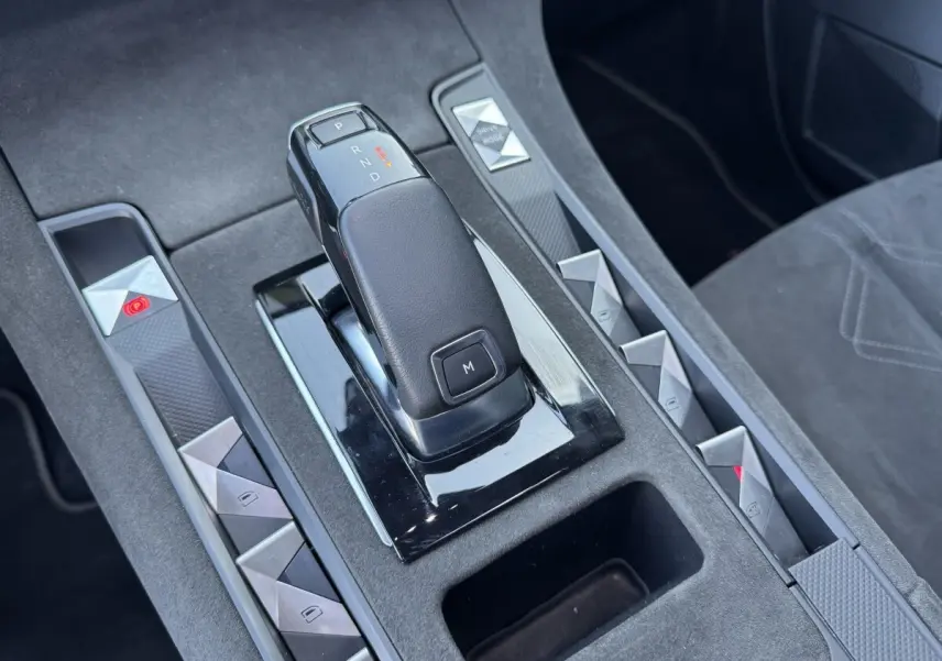 Gros plan sur la console centrale noire du DS7 Crossback avec levier de vitesse automatique et boutons triangulaires argentés.