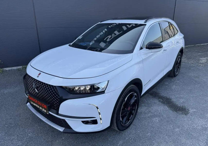 DS7 Crossback blanc en vue 3/4 avant droit, avec calandre noire et jantes noires distinctives.
