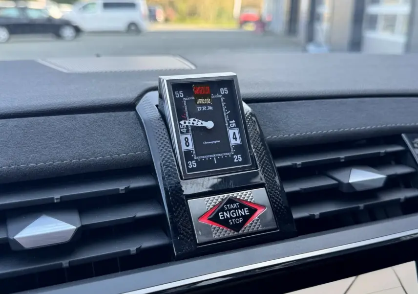 Gros plan sur le tableau de bord du DS7 Crossback blanc, mettant en valeur l'horloge B.R.M et le bouton start/stop rouge.