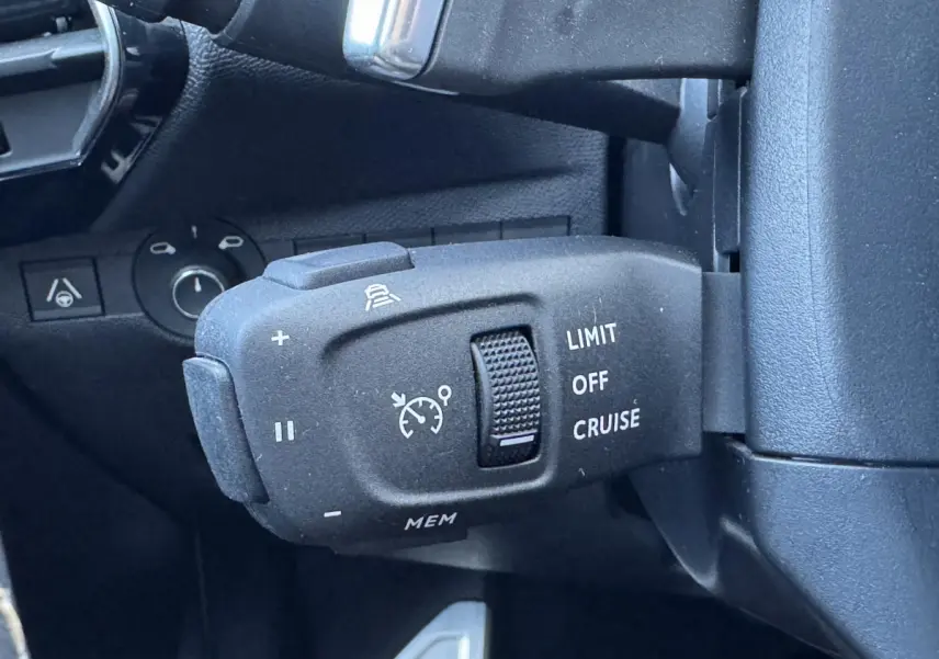 Gros plan sur la commande de régulateur de vitesse du DS7 Crossback blanc, côté gauche du volant.
