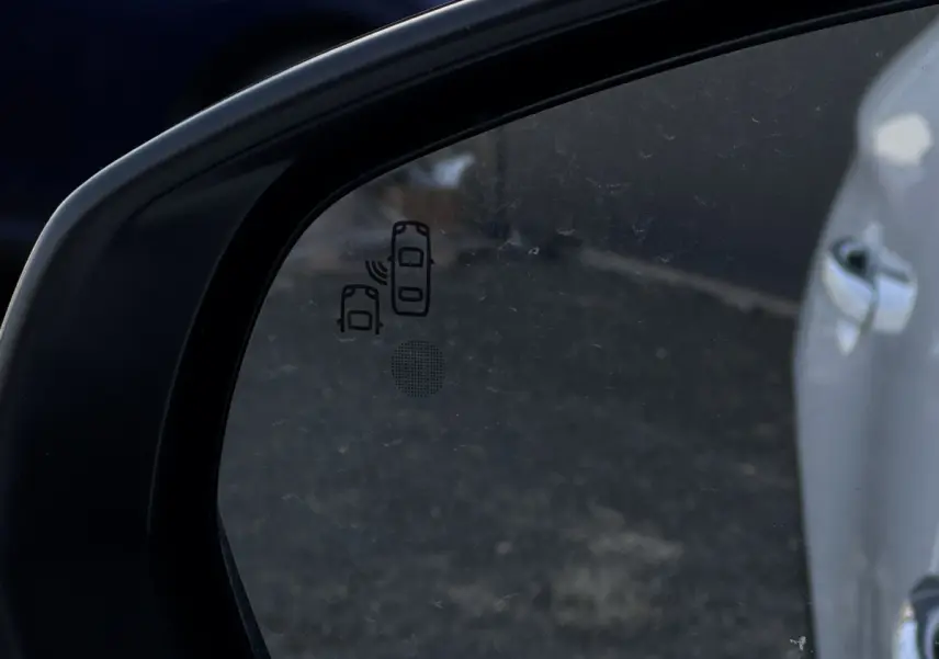 Gros plan sur le rétroviseur côté conducteur d’un DS7 Crossback blanc, avec indication du système d’alerte d’angle mort.