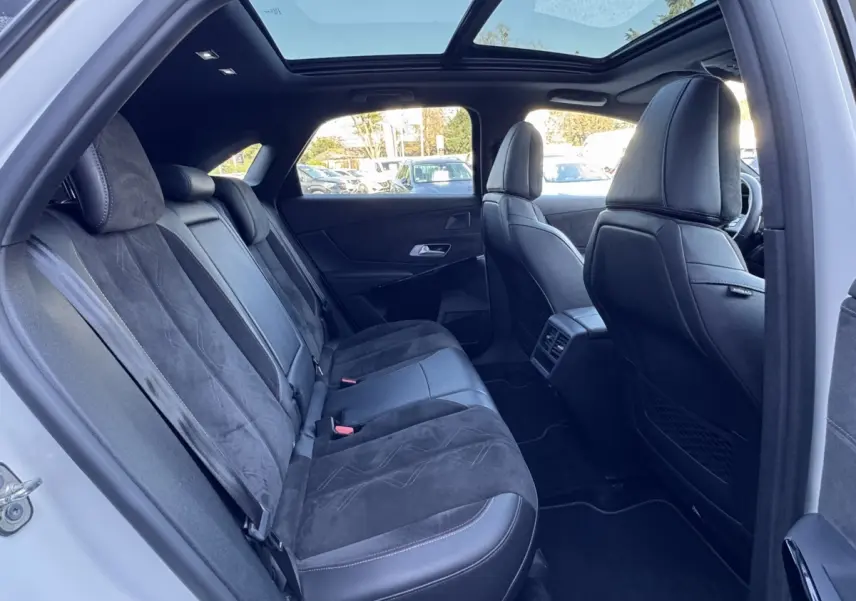 Vue intérieure côté gauche montrant les sièges arrière en cuir noir et alcantara avec toit panoramique du DS7 Crossback blanc.