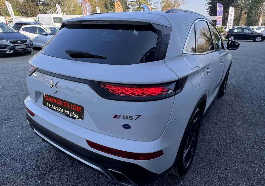 Vue 3/4 arrière droite d'un DS7 Crossback blanc avec feux arrière LED et toit noir brillant.
