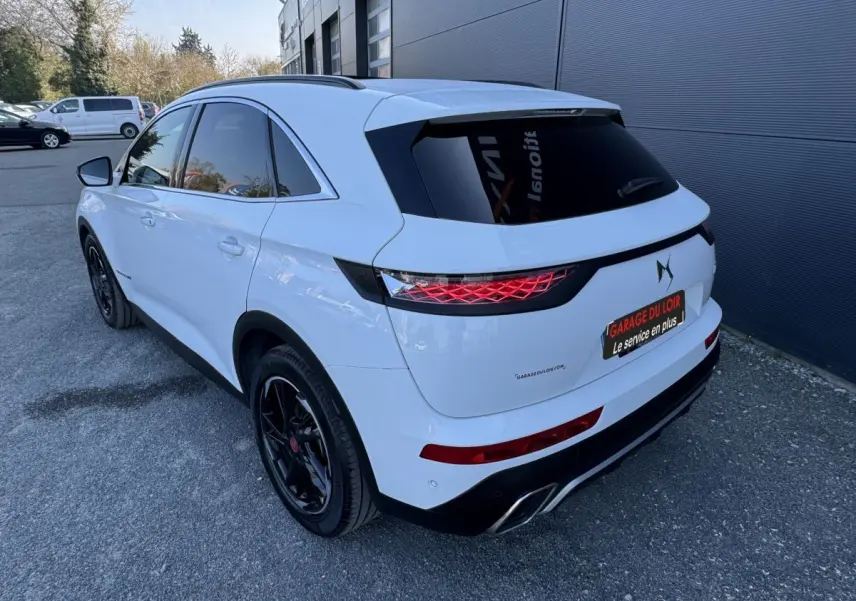 Vue 3/4 arrière droite du DS7 Crossback blanc avec jantes noires et feux arrière LED distinctifs.