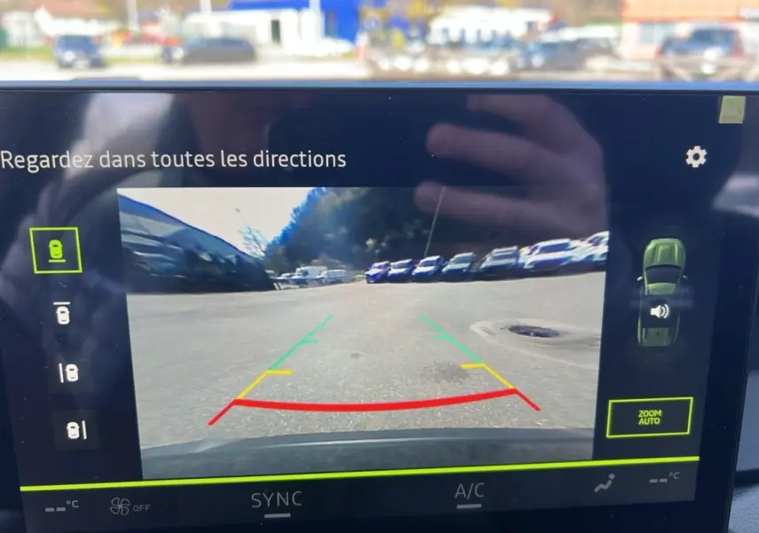 Écran de caméra multiview montrant une vue arrière dégagée du parking du Dacia Bigster vert cèdre.