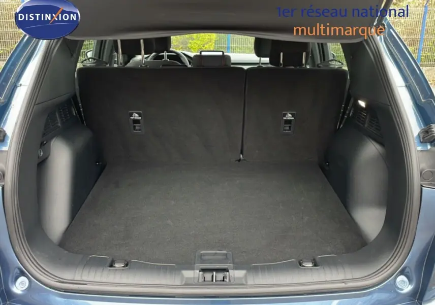 Vue arrière du coffre ouvert d'un Ford Kuga 2024 bleu chrome métal, montrant un espace de chargement propre et spacieux.