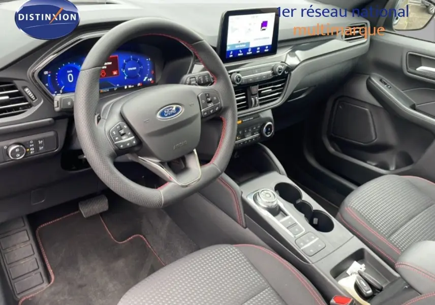 Vue intérieure côté conducteur du Ford Kuga 2024, tableau de bord moderne avec écran tactile et volant cuir noir à surpiqûres rouges.