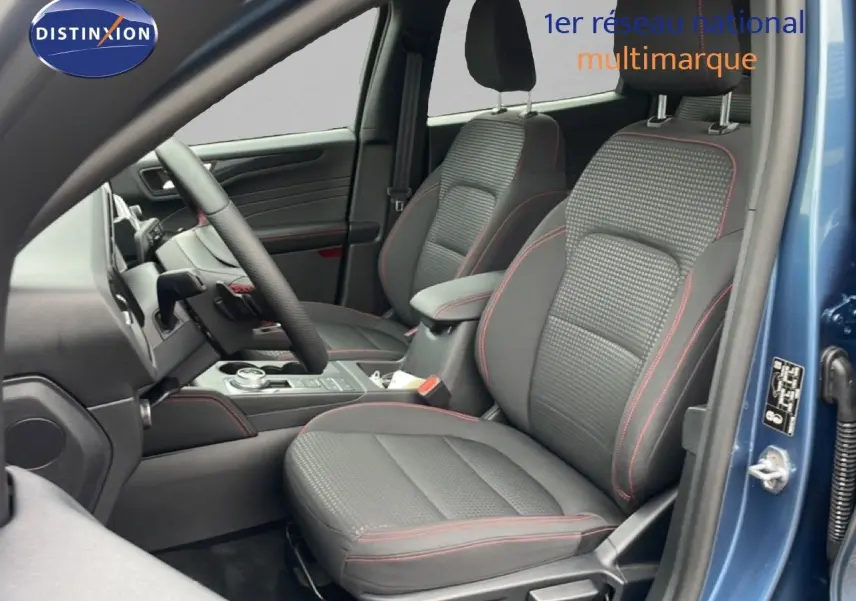 Vue intérieure côté conducteur du Ford Kuga bleu chrome métal 2024, sièges tissu noir avec surpiqûres rouges.