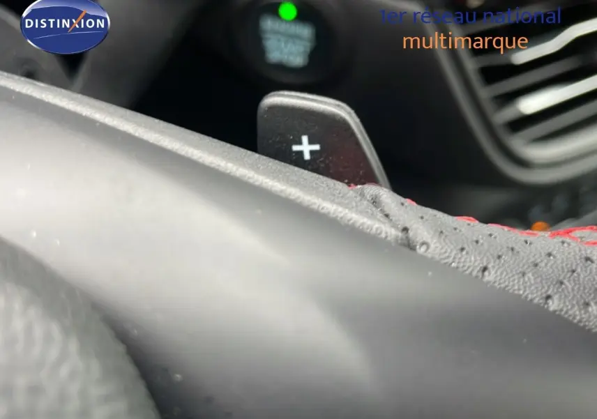 Gros plan sur la palette de changement de vitesse "+" en aluminium noir et cuir perforé avec surpiqûres rouges dans un Ford Kuga 2024.