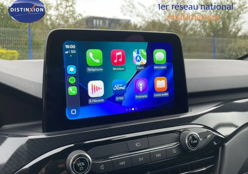 Écran tactile central du Ford Kuga 2024 en bleu chrome, affichant l'interface multimédia avec commandes audio et navigation.