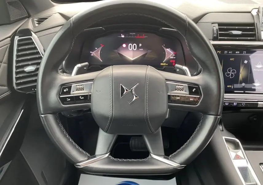 Vue rapprochée du volant en cuir noir du DS7 2024 avec tableau de bord numérique et écran tactile central.