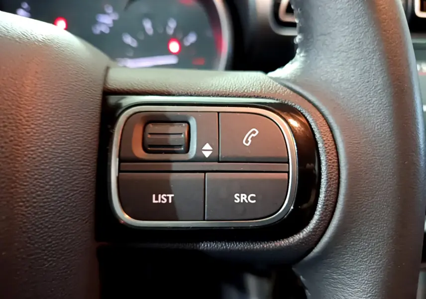 Gros plan sur les commandes gauche du volant cuir du Citroën C3 Aircross 2019, boutons LIST et SRC visibles.