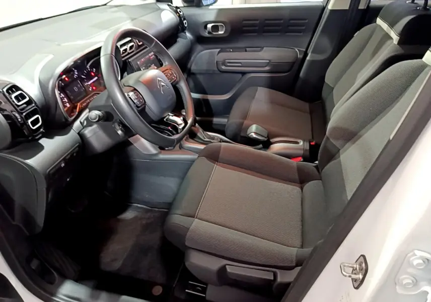 Intérieur avant droit du Citroën C3 Aircross blanc 2019, montrant sièges tissu gris et tableau de bord noir.