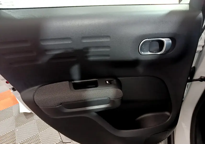 Intérieur de la porte arrière droite noire du Citroën C3 Aircross blanc, avec poignée et bouton de vitre électrique.