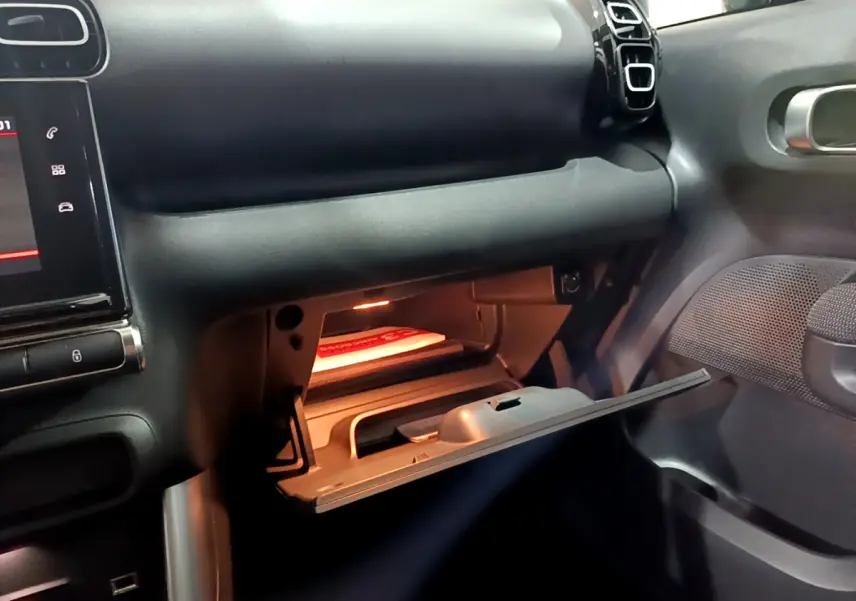 Intérieur du Citroën C3 Aircross 2019, vue du côté passager avec boîte à gants ouverte et tableau de bord noir.