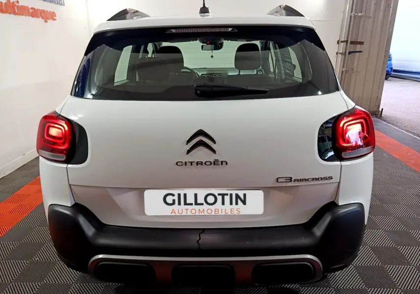 Vue arrière d'un Citroën C3 Aircross blanc avec feux arrière allumés et logo visible sur porte de coffre.