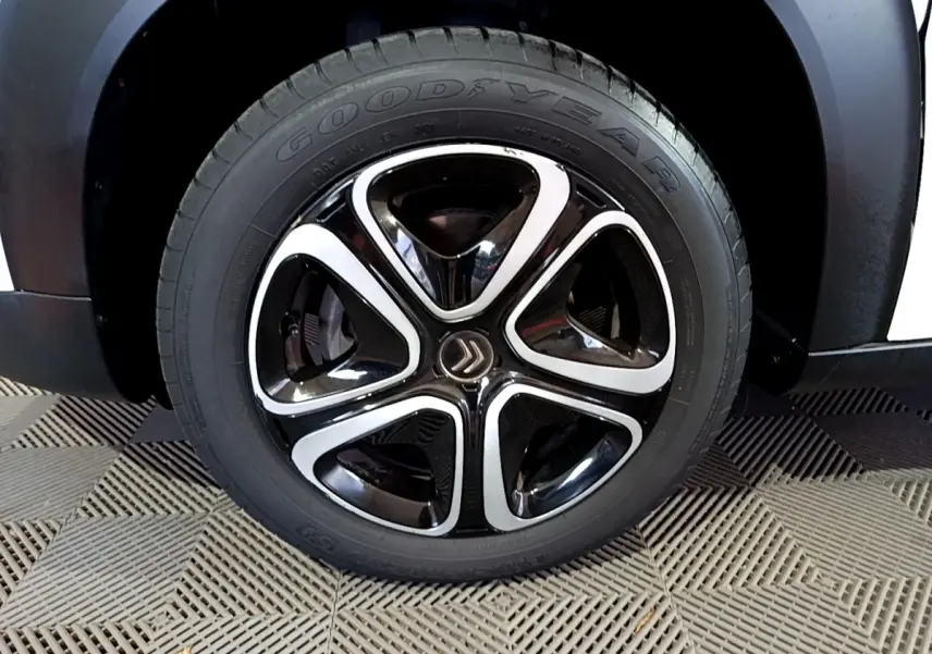 Gros plan sur la roue avant droite blanche du Citroën C3 Aircross avec jante noire et argentée au design distinctif.