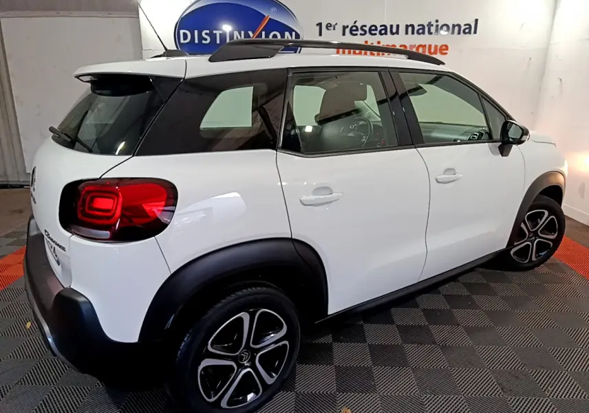 Vue 3/4 arrière droite d'un Citroën C3 Aircross blanc avec toit noir et jantes alliage distinctives.