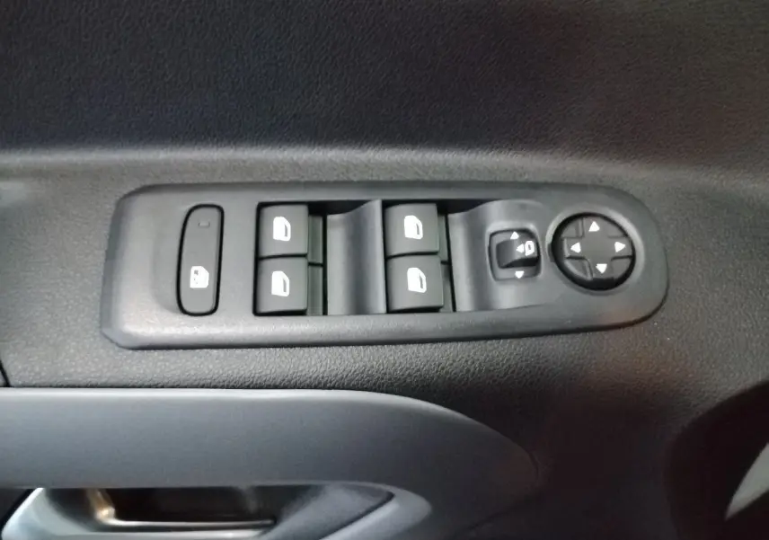 Gros plan sur les commandes de lève-vitres et réglage des rétroviseurs côté conducteur du Citroën Berlingo blanc 2025.
