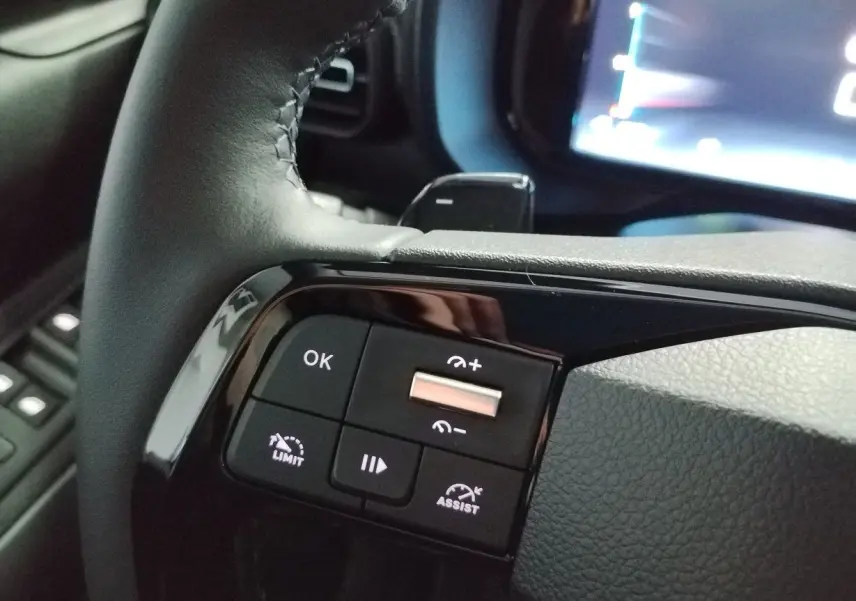 Gros plan sur les commandes noires au volant du Citroën Berlingo blanc, avec touches de régulateur et assistant de conduite.