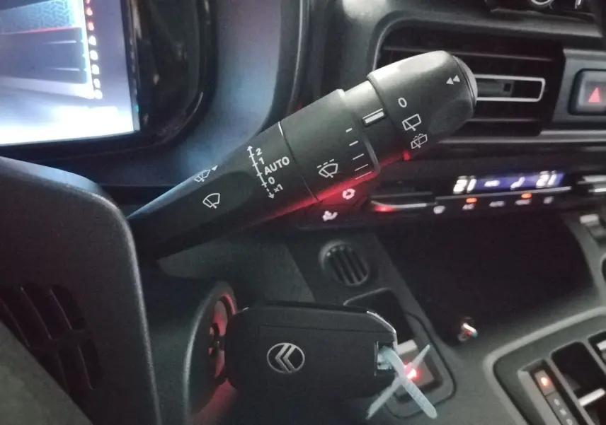 Gros plan sur la commande d’essuie-glace et clé de contact dans l’habitacle du Citroën Berlingo blanc 2025.