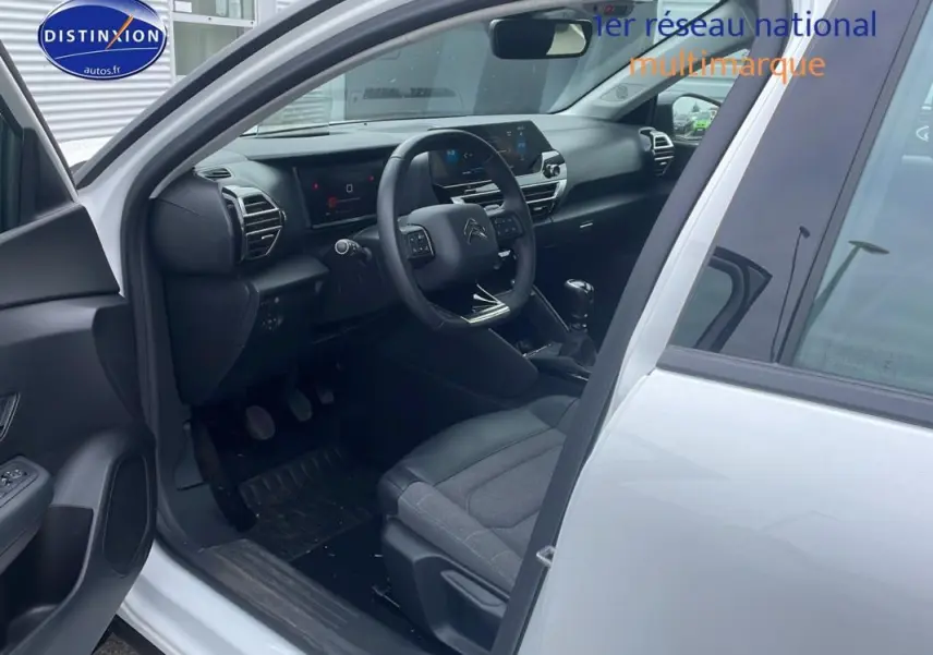 Intérieur côté conducteur d'une Citroën C4 blanche 2022, montrant tableau de bord moderne et sièges gris.