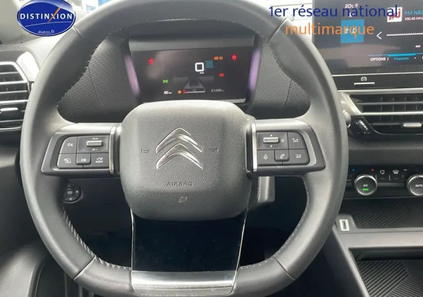 Vue rapprochée du volant cuir noir de la Citroën C4 2022 avec commandes intégrées et tableau de bord numérique.