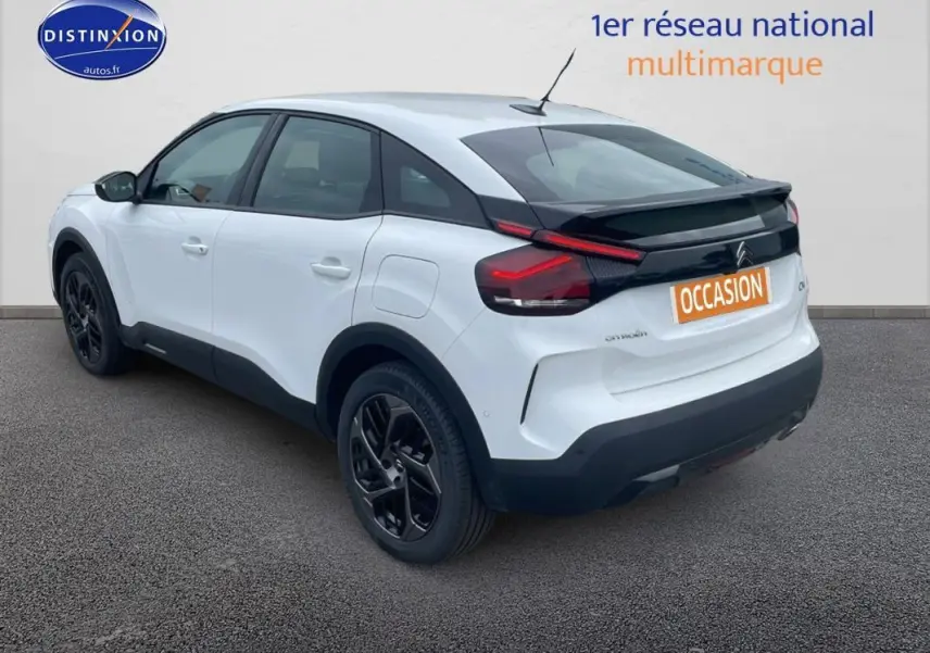 Vue 3/4 arrière droite d'une Citroën C4 blanche 2022 avec jantes alliage noires et bandeau noir arrière.