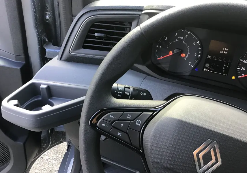 Vue intérieure côté conducteur du tableau de bord et volant du Renault Master gris urbain avec commandes au volant.