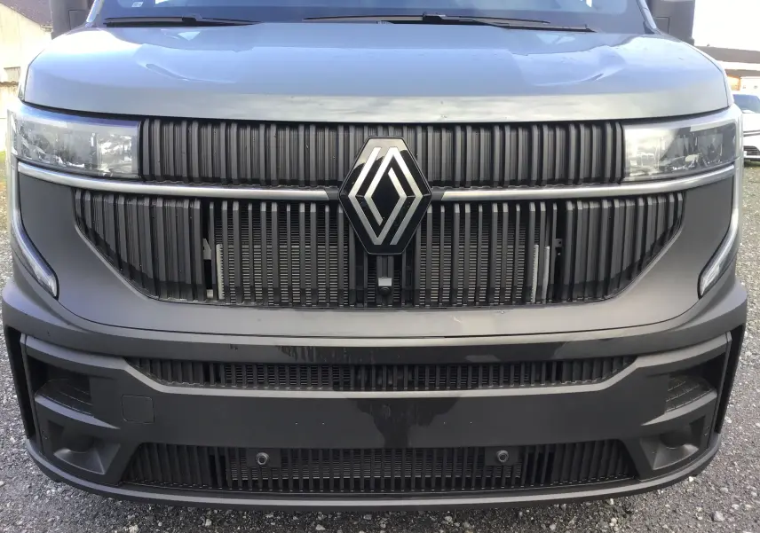 Vue frontale rapprochée du Renault Master gris urbain 2025 avec calandre noire et grand logo Renault central.