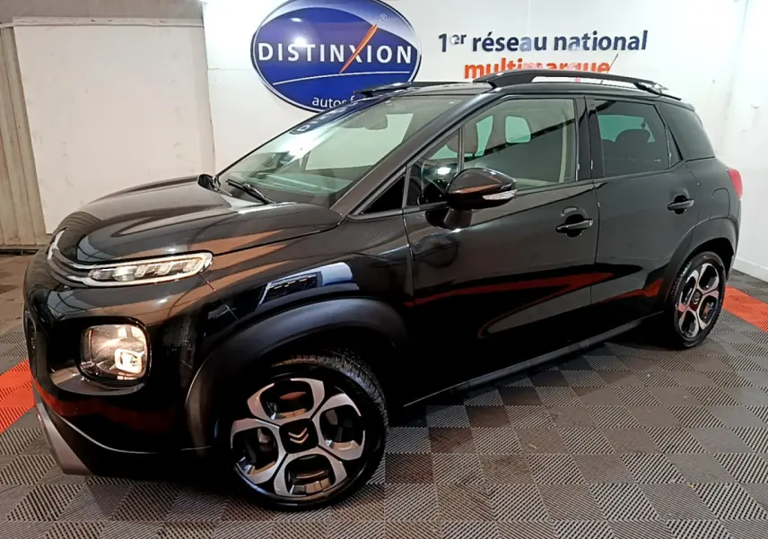 Citroën C3 Aircross noir vue 3/4 avant droit en intérieur, avec jantes distinctives et barres de toit noires.