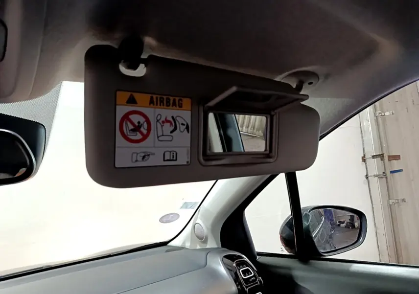 Détail intérieur du pare-soleil côté conducteur avec miroir et avertissement airbag dans une Citroën C3 Aircross noire.