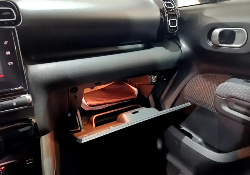 Intérieur du Citroën C3 Aircross noir 2019, vue côté passager sur la boîte à gants ouverte avec éclairage intérieur.