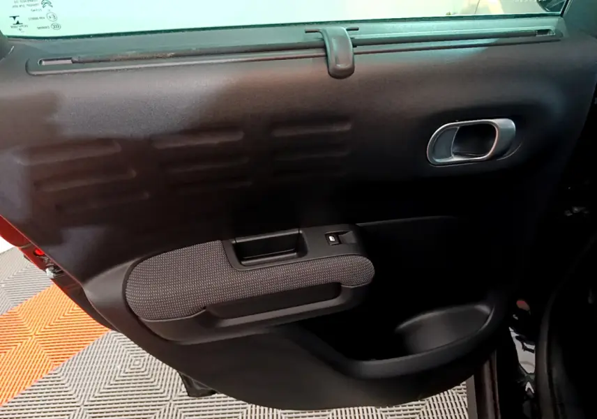 Gros plan sur la porte intérieure côté droit du Citroën C3 Aircross noir, avec poignée argentée et accoudoir texturé.