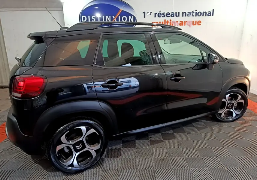 Vue de profil côté gauche d'un Citroën C3 Aircross noir 2019 avec barres de toit et jantes distinctives.
