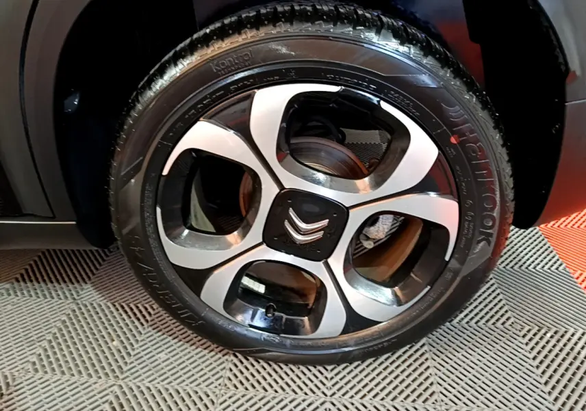 Gros plan sur la roue avant gauche noire du Citroën C3 Aircross avec jante alliage bicolore et logo Citroën central.