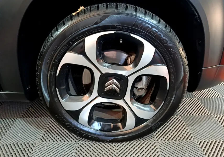 Gros plan sur la roue arrière droite noire du Citroën C3 Aircross PureTech 110 Shine, avec passage de roue et partie de la carrosserie visibles.