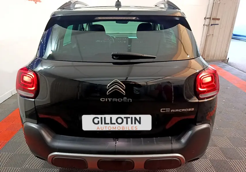 Vue arrière d'un Citroën C3 Aircross noir avec feux arrière allumés et logo distinctif sur un sol à damier.