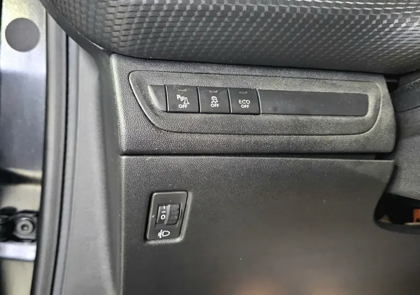 Détail des commandes côté gauche sous le siège conducteur de la Peugeot 208 GT-LINE noir, avec boutons de réglage et désactivation.