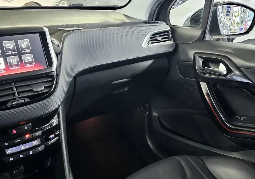 Intérieur avant droit de la Peugeot 208 GT-LINE noir, avec écran tactile et tableau de bord texturé gris.