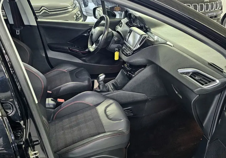 Intérieur noir de la Peugeot 208 GT-LINE 2015 vu côté conducteur, avec tableau de bord et sièges en cuir.