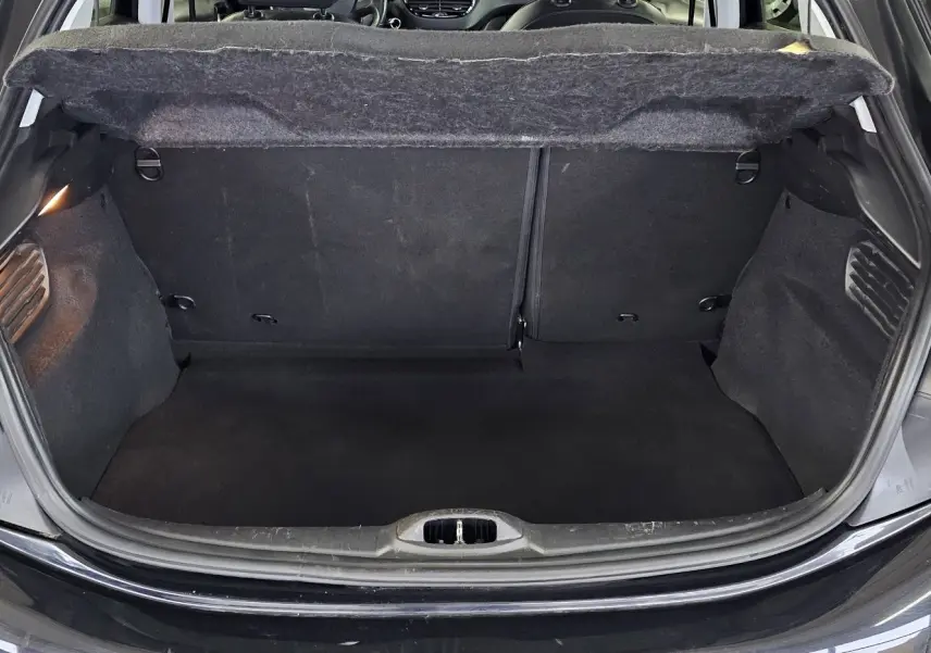 Coffre ouvert en vue arrière d’une Peugeot 208 GT-LINE noire, montrant l’espace de chargement vide et la doublure intérieure.