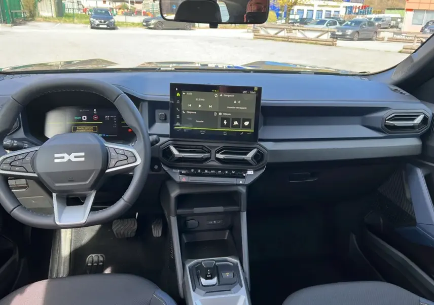 Vue intérieure du tableau de bord du Dacia Bigster 2026, avec volant cuir et écran tactile central noir.